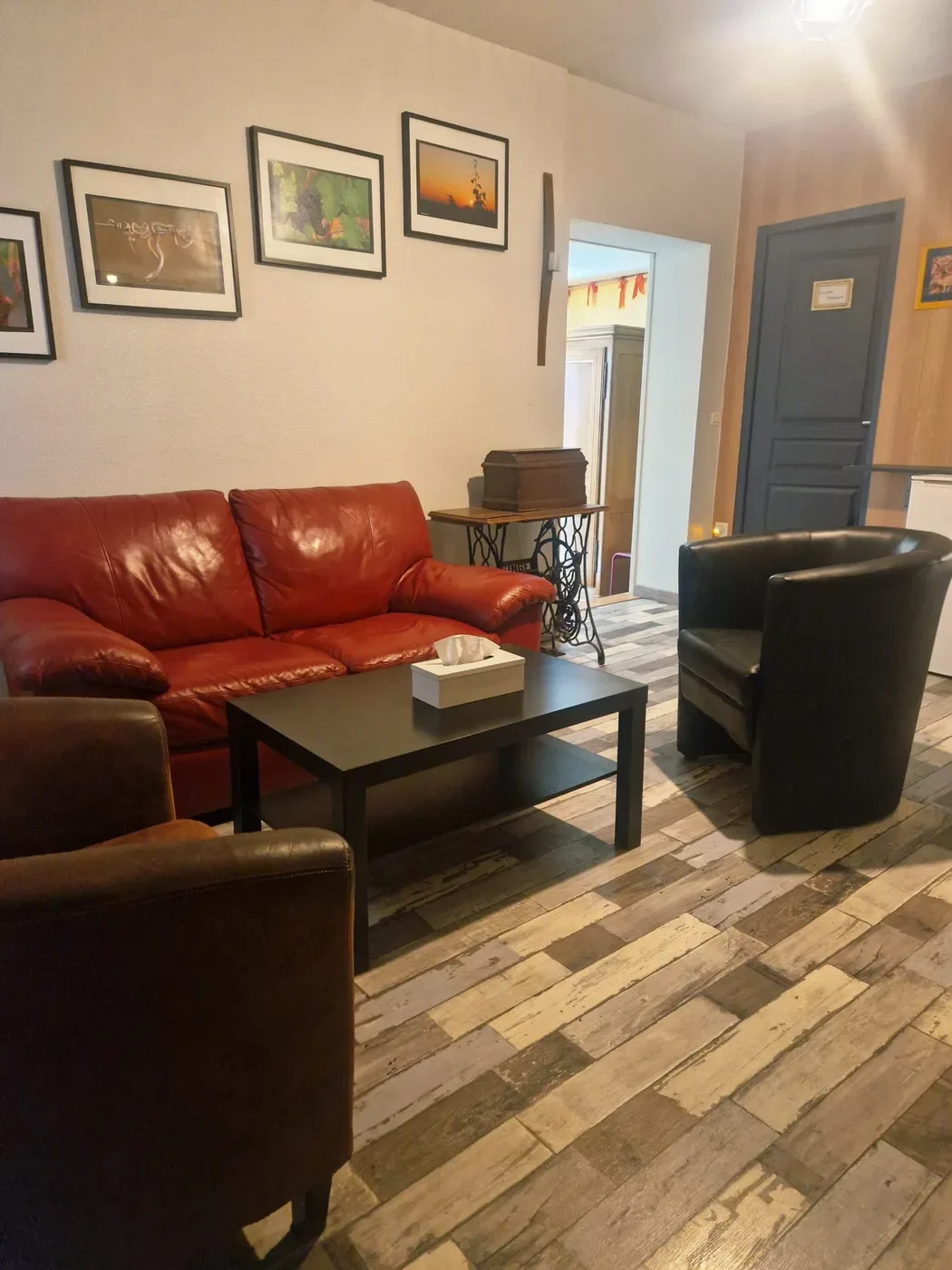 Salon chaleureux avec canapé en cuir rouge et fauteuils club au Clos des Meix